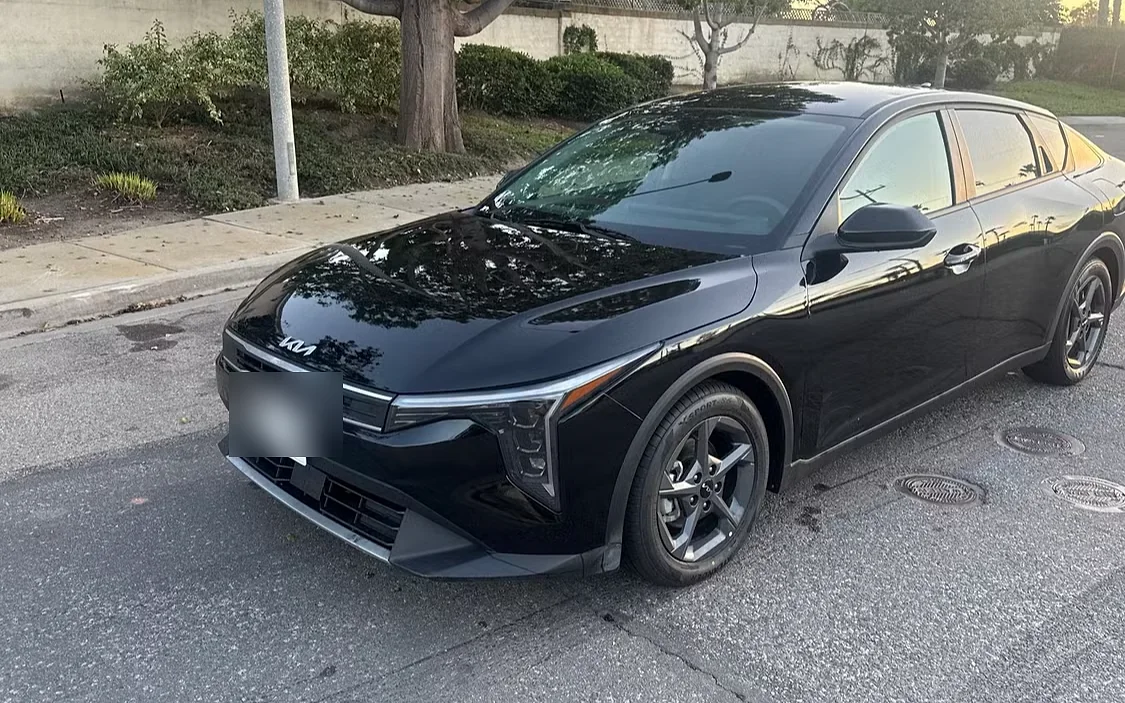 Black Kia K4 sedan from the Evolution Auto Sale fleet photographed at golden hour in Oceanside, California